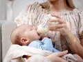 Mama karmi maluszka z butelki, która może być najlepszą butelką antykolkową dla noworodka.