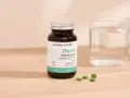 Bouteille de chlorelle Aroma-Zone, 240 comprimés. Pour une cure détox et vitalité, combien de temps faut-il ? Verre d'eau à côté.
