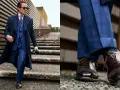 Un giovane uomo con un completo blu a quadri, cappotto scuro e occhiali da sole, cammina con passo sicuro. Un vero old money boy.