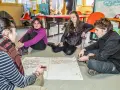 Quatre jeunes discutent autour d'un papier, participant à un mouvement d'éducation populaire. Ils brainstorment des idées pour améliorer une activité.