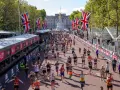 Tysiące biegaczy na trasie maratonu londyn, z flagami Wielkiej Brytanii i Pałacem Buckingham w tle.