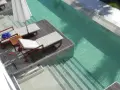 Tumbonas y sombrilla junto a unas piscinas originales de agua cristalina con escalones integrados.