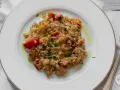 Pyszne risotto z owocami morza, z pomidorkami i natką pietruszki, polane oliwą.