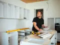 Mężczyzna planuje, jak zabudować przestrzeń nad szafkami kuchennymi, analizując projekt.