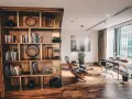 Drewniana biblioteczka z książkami i dekoracjami, obok skórzane fotele i biurko z maszyną do pisania. Styl **modern rustic**.