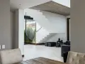 Moderna escalera blanca con un diseño flotante. El **rellano escalera decoracion descansillo escalera** se realza con linternas negras y maceteros.