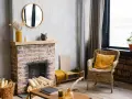 Un camino di mattoni rustico, pronto per essere rinnovato. Legna accatastata, decorazioni e una sedia in vimini invitano al relax.