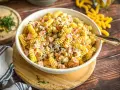 Cremiger Nudelsalat mit Schinken, Erbsen und einem leckeren Dressing, garniert mit frischen Kräutern.