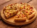 Fette di torta salata patate e salsiccia dorata e invitante, servite su un tagliere di legno.