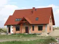 Dom w budowie z czerwonym dachem i oknami dachowymi. Wnętrze z potencjałem na wysoki, **sufit katedralny**.