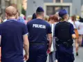 Policja w patrolu, kiedy policja szuka dłużnika. Dwóch funkcjonariuszy w mundurach idzie ulicą wśród tłumu ludzi.