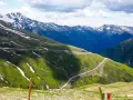 Malownicze francja alpy z krętą drogą wijącą się po zielonych zboczach. Śnieg na szczytach gór i błękitne niebo.