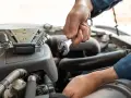 Mechanik dokonuje wymiany kompresora klimatyzacji, używając klucza do odkręcenia śrub.