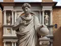 Estatua de mármol de un hombre con barba y túnica, sosteniendo un globo terráqueo, frente a un edificio renacentista.