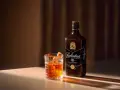 Elegancki drink Rob Roy z whisky Ballantine's 10 Year Old, podany w szkle z lodem i skórką pomarańczy.
