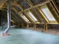Aménagement des combles d'une maison Phénix : charpente, fenêtres de toit, isolation et gaine de ventilation en cours.
