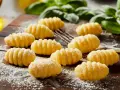 Domowe gnocchi, gotowe do przygotowania według ulubionego gnocchi przepisu. Pachnące bazylią i posypane mąką, czekają na sos.