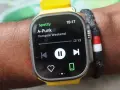 En handled med en smartklocka som visar Spotify-appen. Låten "A-Punk" av Vampire Weekend spelas.