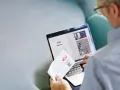 Mężczyzna loguje się do portalu eOS fundusz inwestycyjny. Na ekranie laptopa widnieje formularz logowania i informacje o inwestycjach.