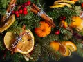 Pomarańcze na choinkę jak zrobić? Suszone plastry pomarańczy, mandarynki, laski cynamonu i czerwone owoce na gałązkach świerku tworzą naturalną ozdobę.