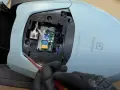 En person med svarta handskar skruvar på ett kretskort inuti en ljusblå Electrolux dammsugare, märkt "PURE D8.2 SILENCE".