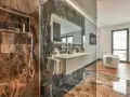 Bagno di lusso con doccia e vasca. Rubinetteria Bossini cromata, lavabo sospeso e specchio illuminato. Marmo scuro e parquet.