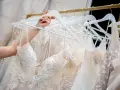 Une main choisit une robe de mariée, révélant la beauté des dentelles et des broderies. Quel tissu pour robe de mariée ? Ici, la délicatesse est reine.