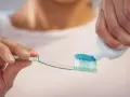 Nakładanie niebieskiej pasty do zębów z fluorkiem sodu na szczoteczkę.