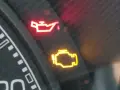 Cruscotto auto con spia dell'olio accesa in rosso e spia motore gialla. Urgente controllo.