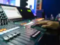 Hand bedient Mischpult für professionelles music management. Lichter und Regler zeigen die komplexe Steuerung.