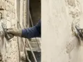 Application d'un enduit pierre vue sur un mur ancien. Un artisan applique le mortier avec une truelle, révélant la texture brute des pierres.