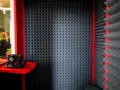 Cabina insonorizzata con pannelli fonoassorbenti, cuffie e tablet. Ideale per registrazioni audio.