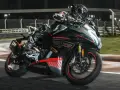 Un pilota in tuta nera sfreccia in pista con la CF Moto 450 SR, puntando alla velocità massima.