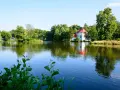 Malowniczy kościół na wodzie w Zwierzyńcu, otoczony zielenią i odbijający się w spokojnej tafli jeziora.