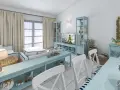 Un soggiorno in stile marinaro con mobili azzurri, cuscini a righe, ancore decorative e un tocco di stile da polo e scarpe da barca.