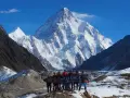 Grupa ludzi z banerem przed majestatycznym szczytem K2 w Karakorum. To wyzwanie w górach Pakistanu.