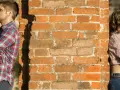 Un homme et une femme se tournent le dos, appuyés contre un mur de briques. Peut-on fixer quelque chose sur un mur mitoyen ?