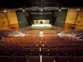 Pusta widownia Teatru Muzycznego im. Danuty Baduszkowej. Pomarańczowe fotele czekają na widzów, scena gotowa na spektakl.