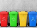 Czerwony, zielony, żółty i niebieski pojemnik na śmieci z symbolem recyklingu. Różne kolory pojemników na śmieci ułatwiają segregację.