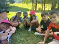 Groupe d'enfants souriants assis dans l'herbe, certains tenant des cartes.