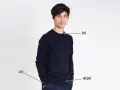 Un homme porte un pull bleu marine. Le tissu pul endroit envers est visible sur le bord du pull.