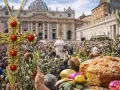 A jeweled cross, palm branches, and Easter treats in front of a crowd gathered for Holy Week in Italy.