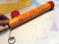 Seenot-Leuchtrakete mit roter Kappe und Anleitung auf einer Seekarte.