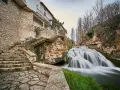Escaleras de piedra y un caserío se funden con la cascada en la Alcarria Alta.