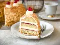 Ein Stück einer köstlichen Torte mit Buttercreme und roter Marmelade, umhüllt von gehackten Nüssen. Perfekt für die besten Torten Rezepte!