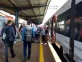 Ludzie czekają na pociąg na stacji w Lęborku. W tle widać budynek dworca i peron.