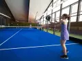 En kvinna i lila klänning spelar padel. Hon är redo att slå bollen på den blå banan.