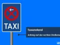 Verkehrsschild "TAXI" mit Pfeil nach links und rotem Verbotsschild. Text: "Taxenstand. Anfang auf der rechten Straßenseite.