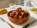 Un cuenco de rabo de cerdo frito, servido con pan, ensalada y agua.