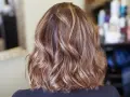 Piękne, falowane włosy z subtelnymi refleksami blond, które dodają im głębi i blasku.